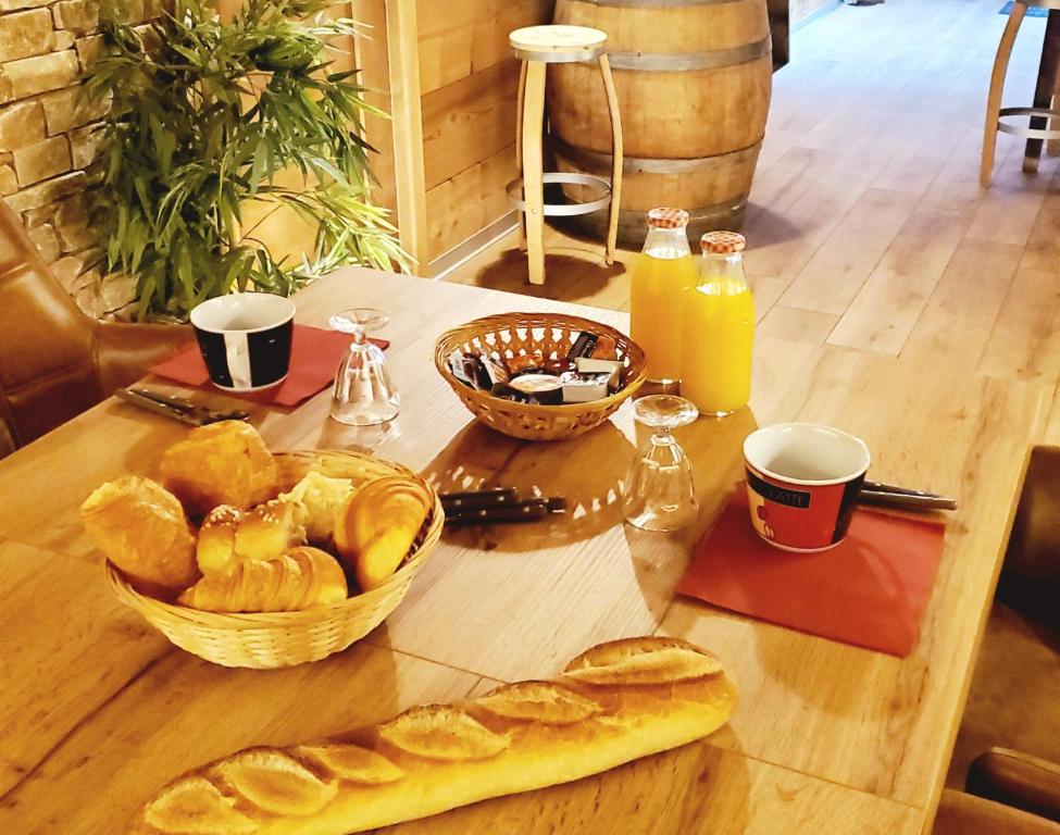 una mesa cubierta con una cesta de pan y zumo de naranja en DEL VINO bar à vin & guitares, en Orchamps-Vennes