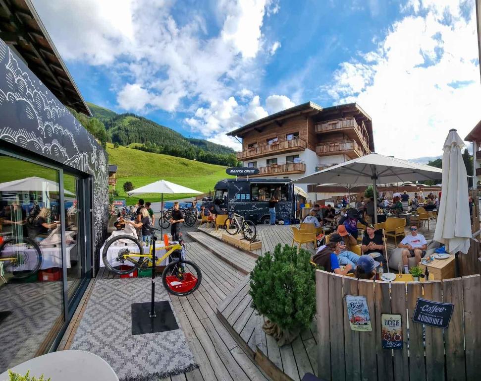 un grupo de personas sentadas en mesas frente a un edificio en SKILL Mountain Lodge - Ski und Bike Hostel inklusive JOKER CARD en Saalbach Hinterglemm