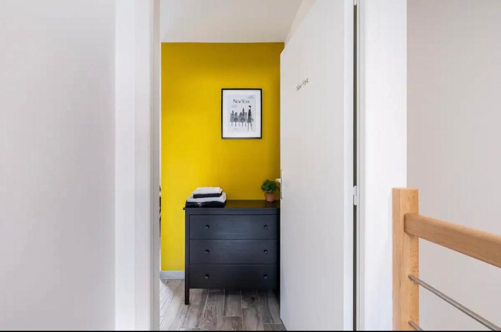 un couloir avec une commode noire et un mur jaune dans l'établissement La villa Hérault, à Cholet