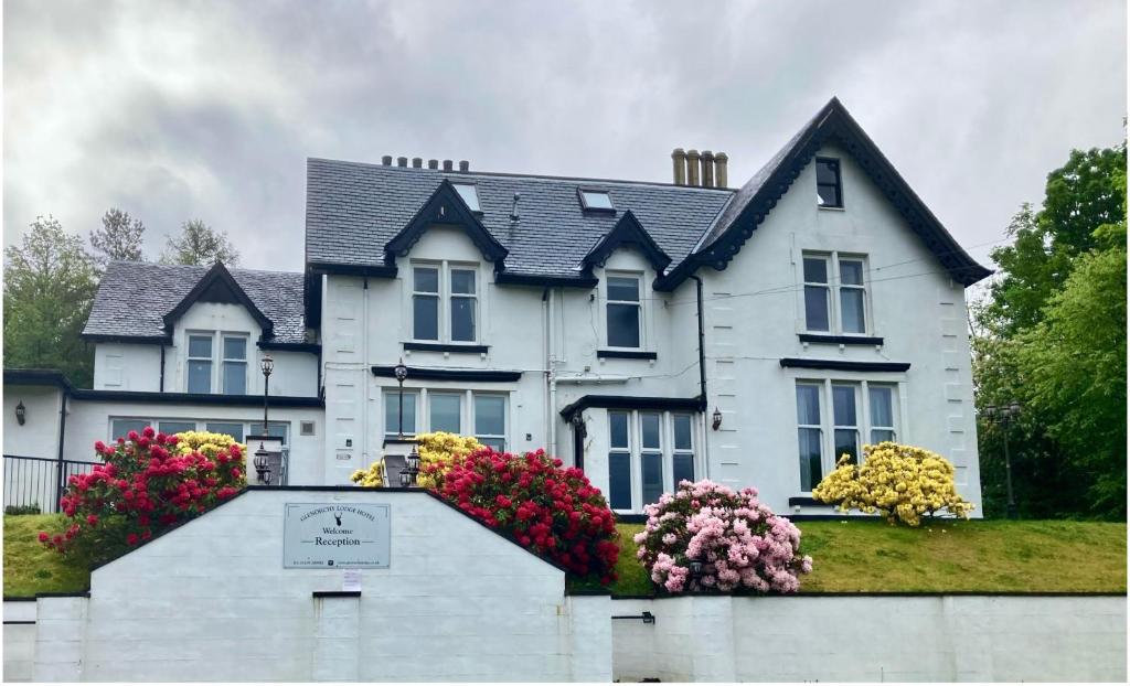 ein weißes Haus mit Blumen davor in der Unterkunft Glenorchy Lodge-Rooms Only in Dalmally