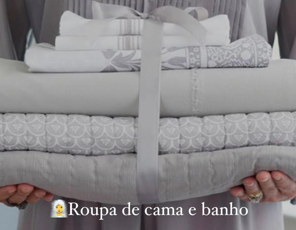 a person holding a stack of white towels at Laguna Airbnb 1706B in Sao Paulo