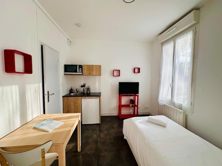 une chambre avec deux lits, une table et une cuisine dans l'établissement Lakanal 1 - Studio Prébendes Tours, à Tours