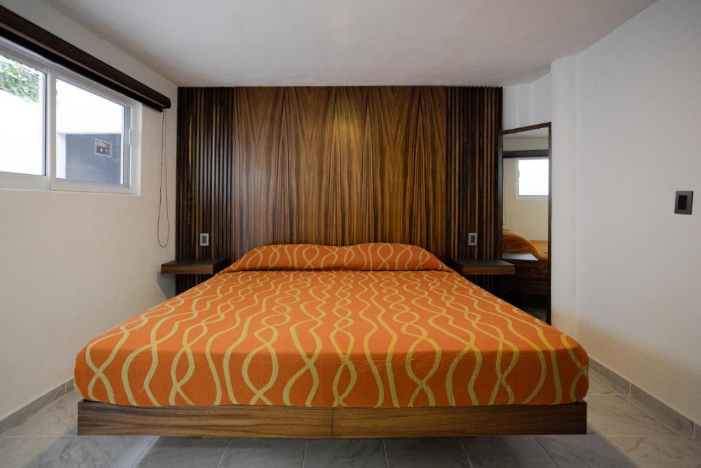 a bedroom with a bed with an orange bedspread at Hotel El Rincón in San Francisco del Rincón