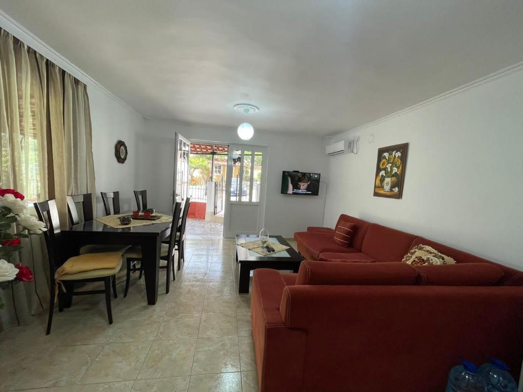 ein Wohnzimmer mit einem roten Sofa und einem Tisch in der Unterkunft Isufi House in Delvinë