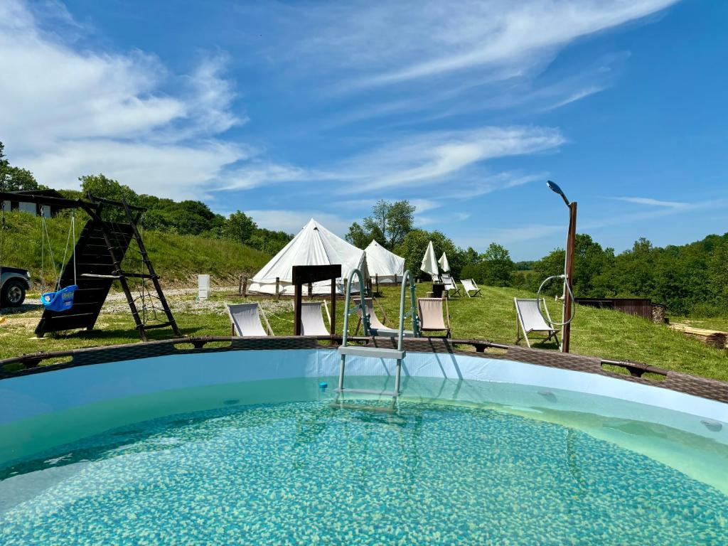 a pool with chairs and tents in the background at Glamping Bieszczady z basenem in Solina