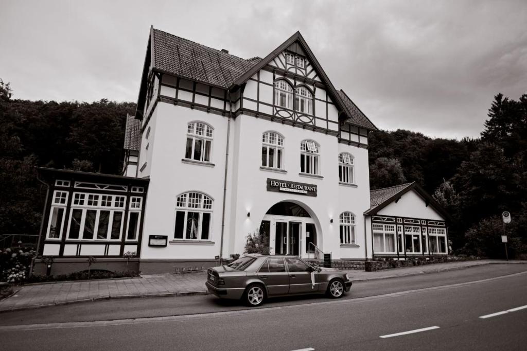 a car parked in front of a large white building at Hotel Müllers im Waldquartier in Bad Essen