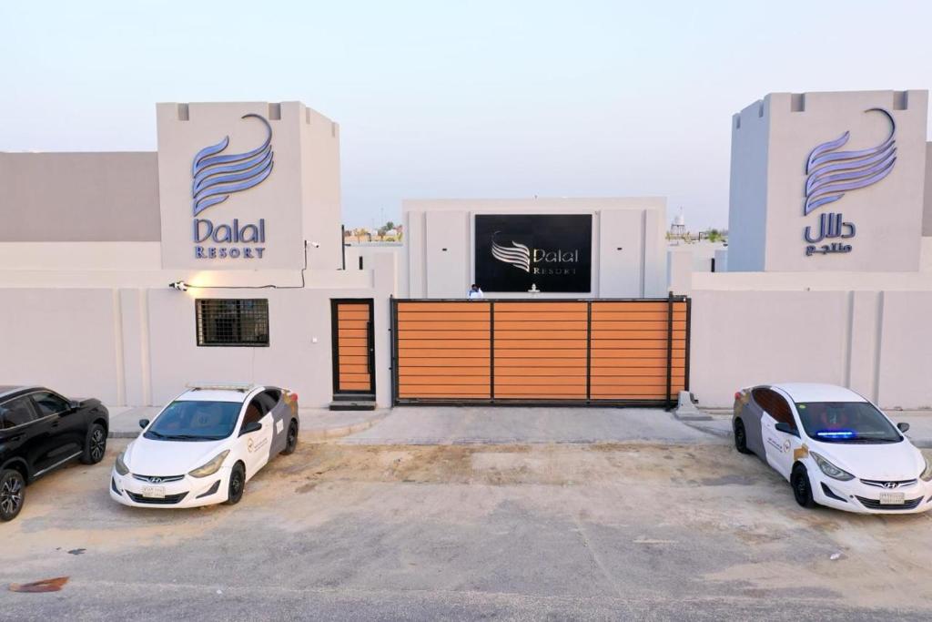 dois carros estacionados num parque de estacionamento em frente a um edifício em منتجع دلال الفندقي Dalal Hotel Resort em Dammam