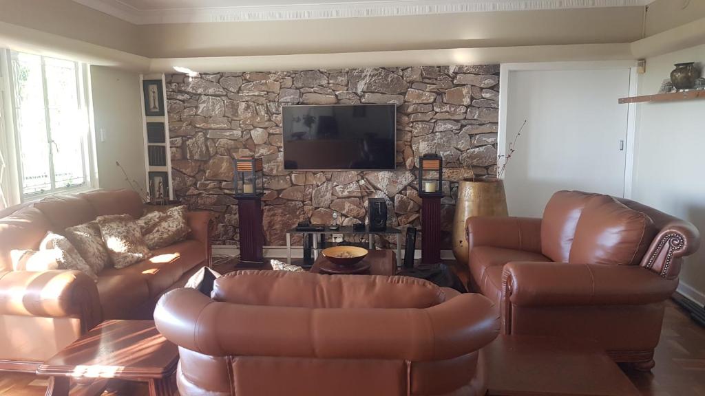 a living room with leather furniture and a stone wall at Multiplex with a view in Durban