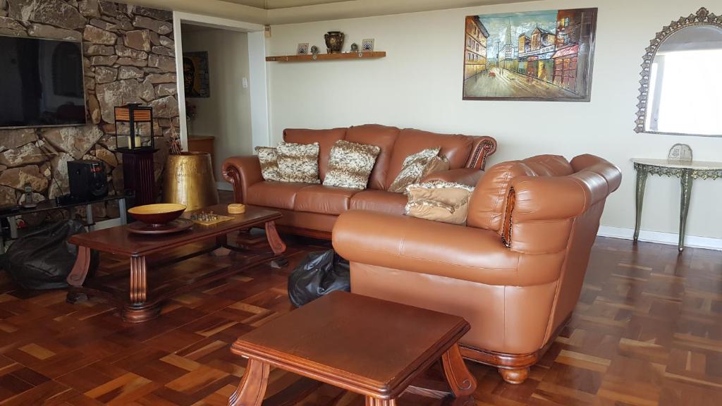 a living room with a leather couch and a table at Multiplex with a view in Durban
