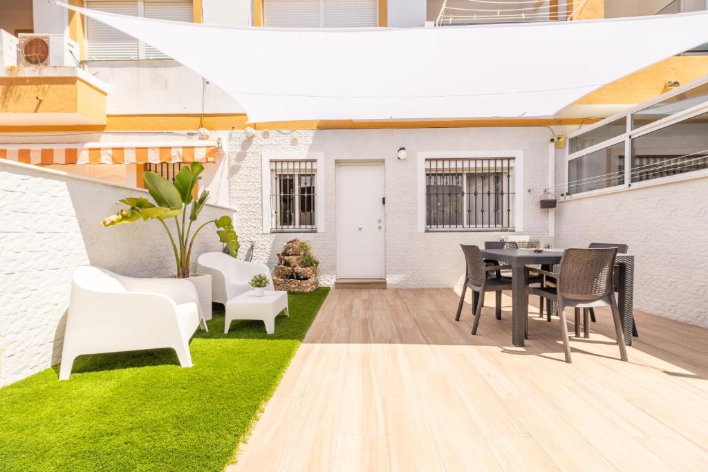 un patio con una mesa negra y sillas blancas en Apartamento Playa La Barrosa en Chiclana de la Frontera