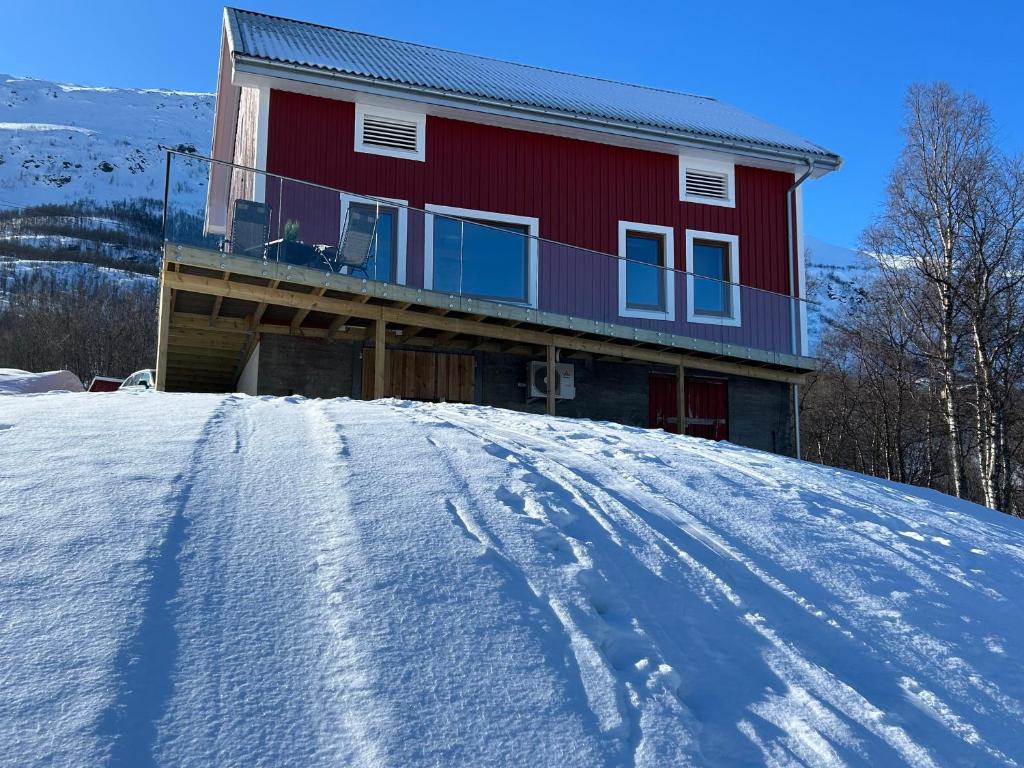 czerwony dom na szczycie pokrytego śniegiem wzgórza w obiekcie Leirvåg w mieście Bukta