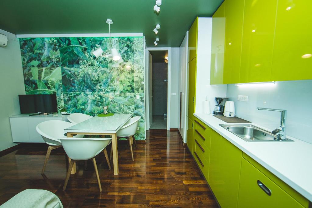 une cuisine avec des armoires vertes, une table et des chaises dans l'établissement Luxury Rooms and Apartment Silente Bacvice, à Split