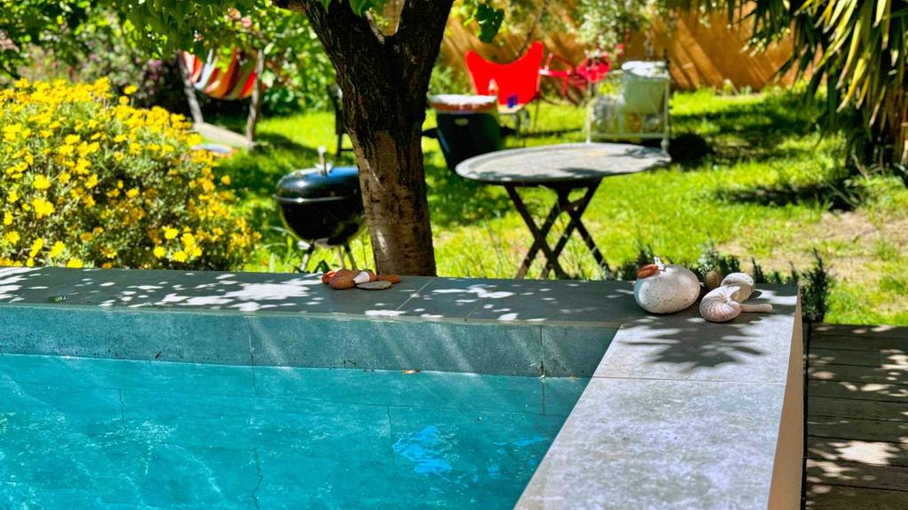 einen Hinterhof mit einem Pool, einem Stuhl und einem Tisch in der Unterkunft Piscine & Sauna Maison au Coeur de Marseille in Marseille