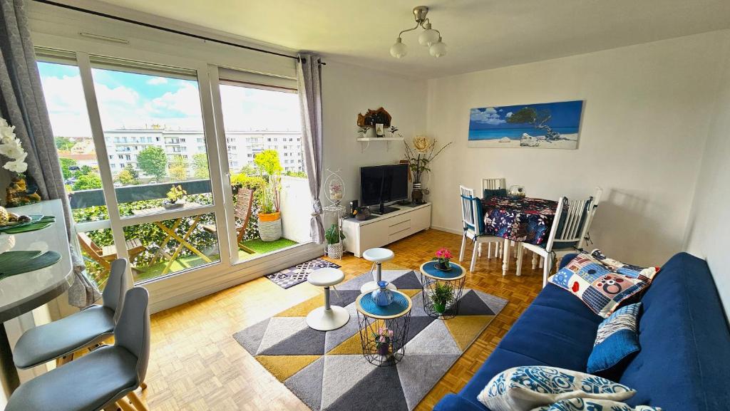 - un salon avec un canapé bleu et une grande fenêtre dans l'établissement Appartement avec balcon proche Paris & Disneyland, à Champigny-sur-Marne