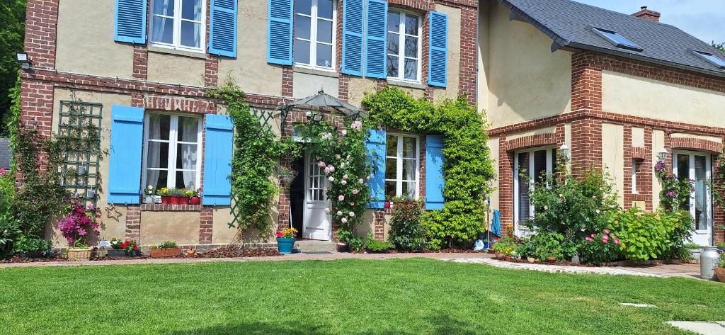 Una gran casa de ladrillo con persianas azules y un patio en La mare aux petits diables en Équemauville