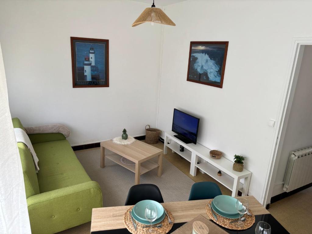 ein Wohnzimmer mit einem grünen Sofa und einem TV in der Unterkunft Maison de pêcheur in Bernières-sur-Mer