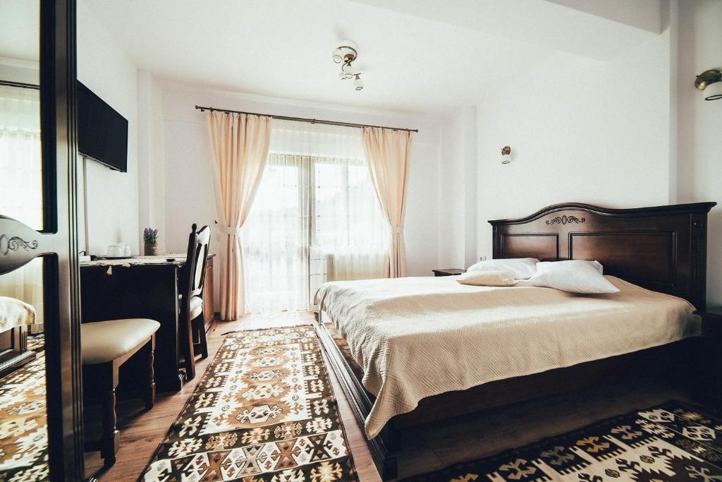 una camera da letto con un letto, una scrivania e una finestra di Conacul Domnitei a Gura Humorului