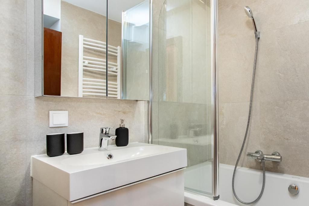 La salle de bains est pourvue d'un lavabo blanc et d'une douche. dans l'établissement Wolfgangthal Apartments in Bad Ischl City Center am TRAUNKAi, à Bad Ischl