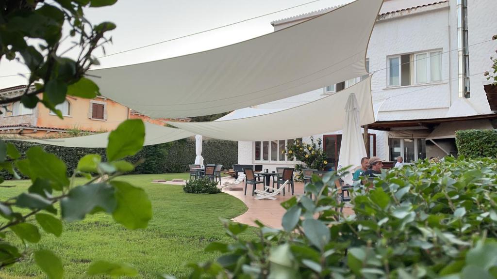 a man sitting in a yard under a white tent at HOTEL al FARO ,SPIAGGIA LA CINTA ,SAN TEODORO in San Teodoro