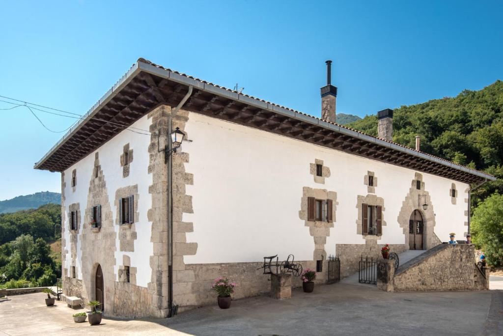 a large white building with trees in the background at Casa rural Iturrikoa in Urritzola