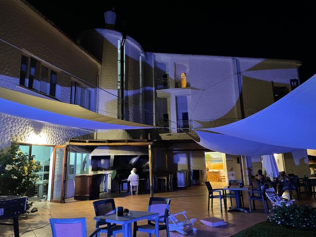 a building with a patio with tables and chairs at night at HOTEL al FARO ,SPIAGGIA LA CINTA ,SAN TEODORO in San Teodoro