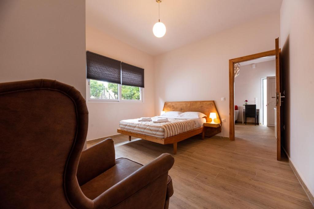 a bedroom with a bed and a chair and a mirror at Serenity - Brand New Apt Near Athens Int Arpt in Spáta