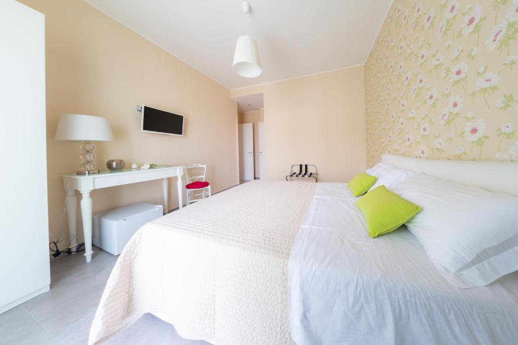 una camera bianca con letto bianco e cuscini verdi di B&B Attico 160 a Catania