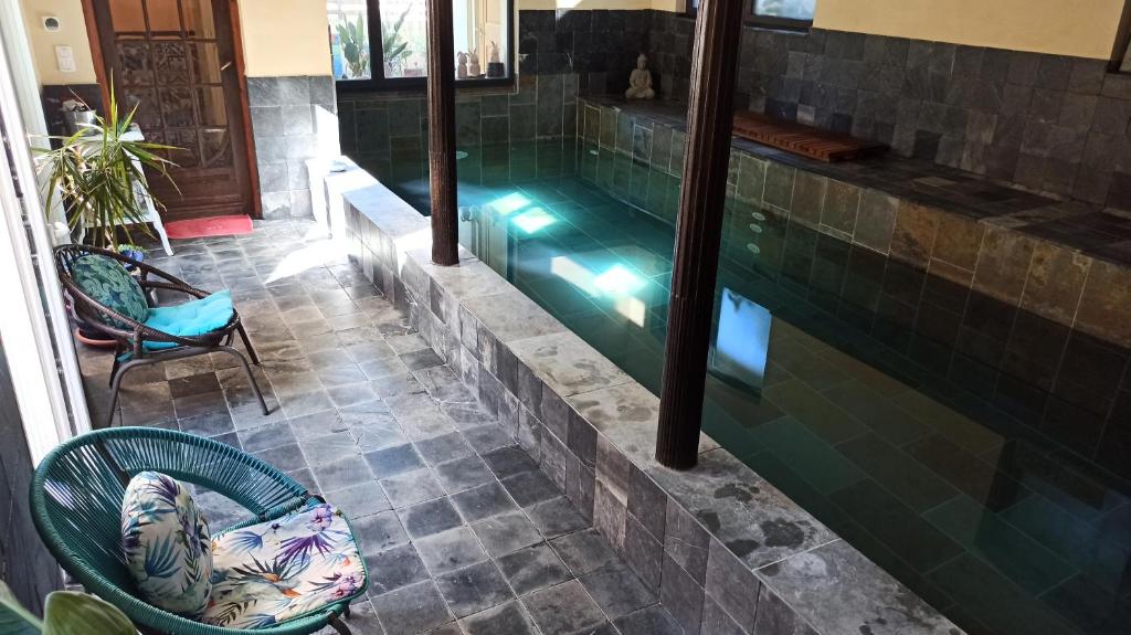 a pool in a house with a chair and a table at Chambre d'Hôtes La Grenade Bleue in Pons