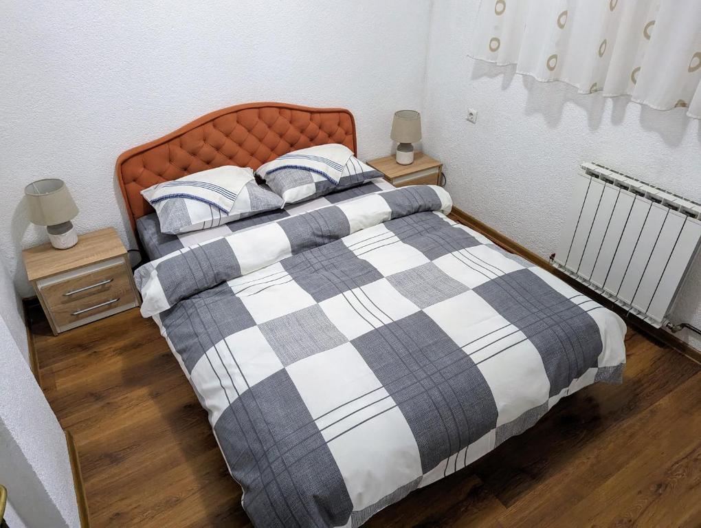 Cama con manta y almohadas a cuadros en Apartment LAMI - Kalibunar, Travnik, en Travnik