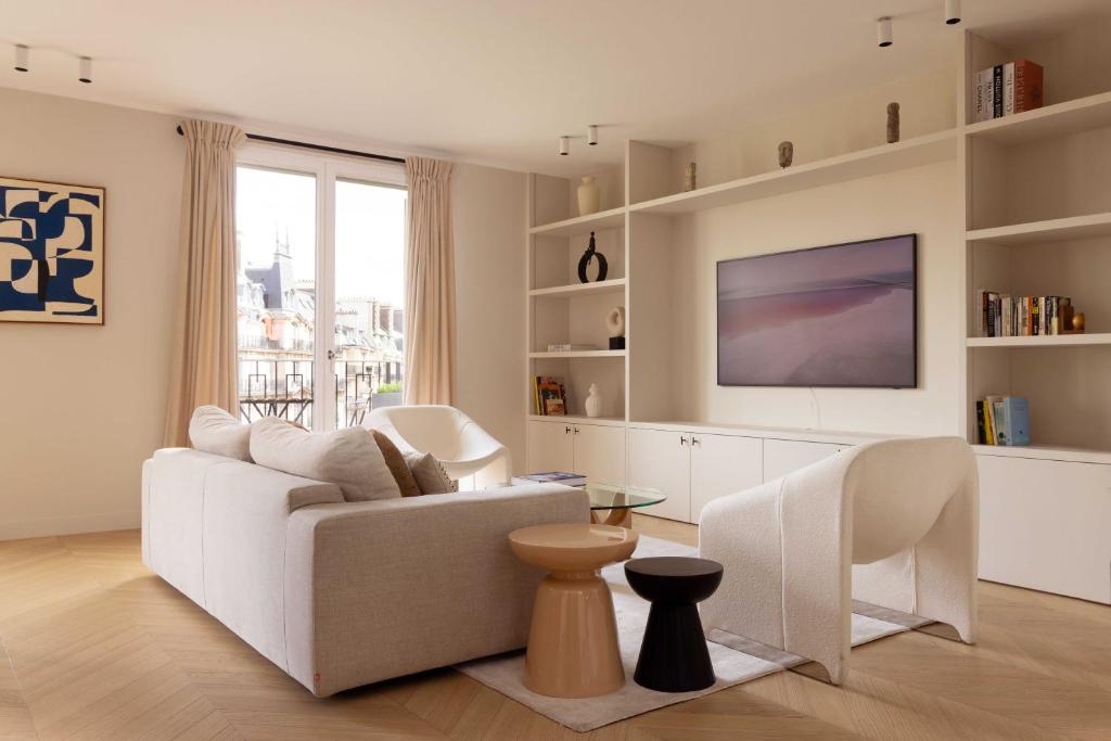 a living room with a white couch and a tv at Luxurious Home in Triangle d'Or Eiffel Tower View in Paris