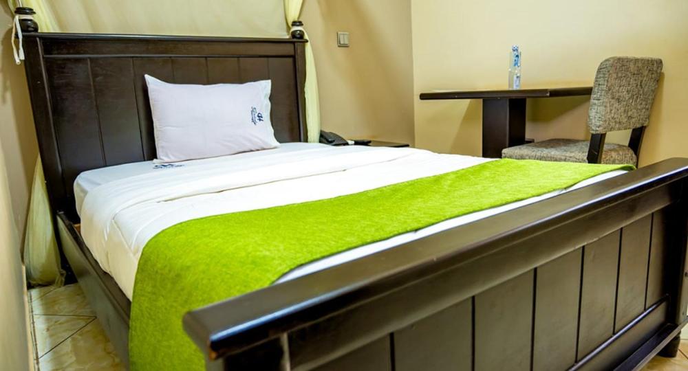 ein Bett mit einer grünen Decke und einem Stuhl in einem Zimmer in der Unterkunft Grady Hotel in Bulindo