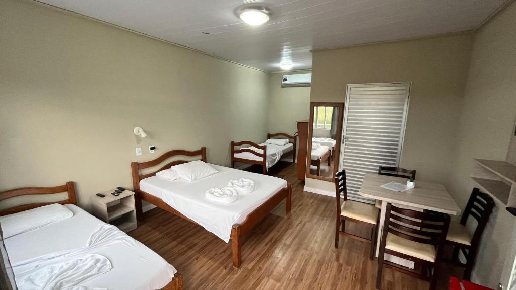 a room with two beds and a table and chairs at ECO CHALÉ PARK CACHOEIRAS in Presidente Figueiredo
