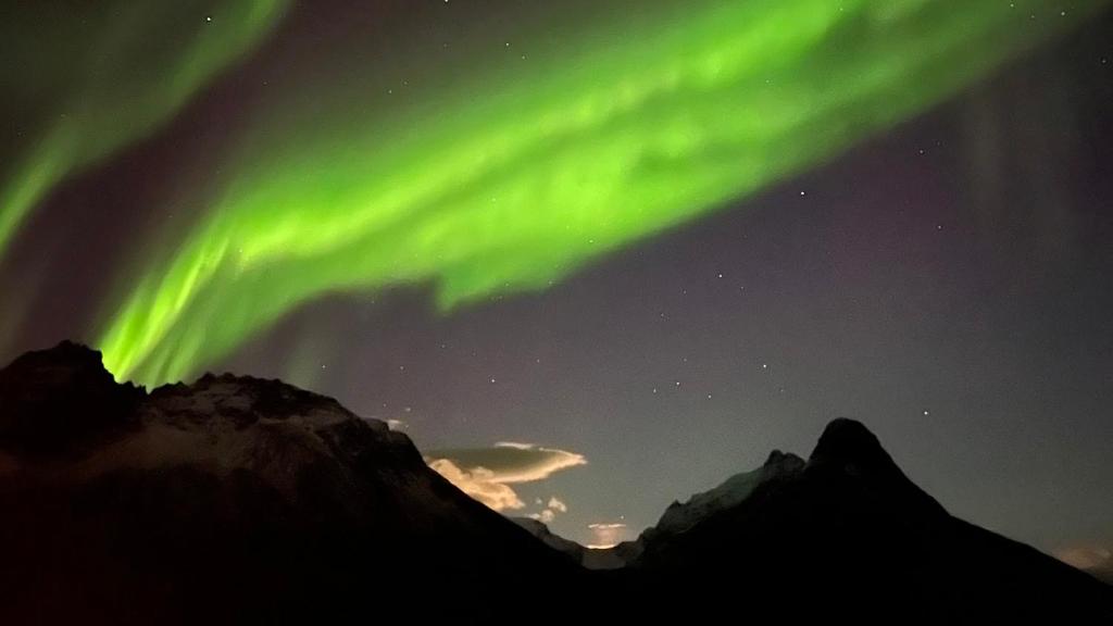 an aurora in the sky over the mountains at Welcome Inn Hotel Lyngskroa in Oteren