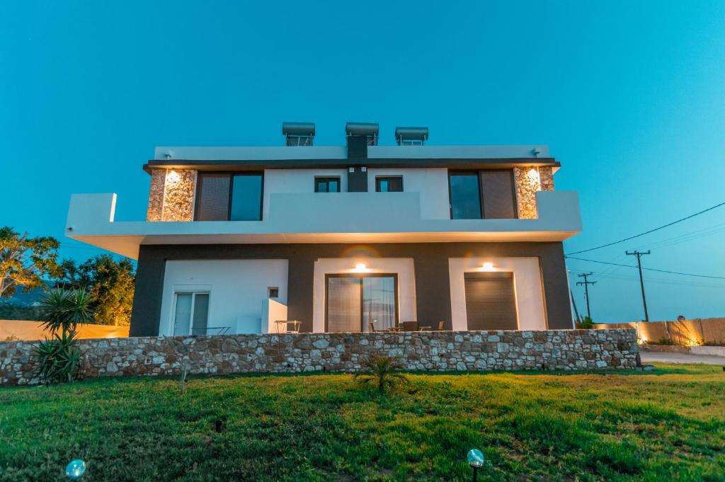 a large white house with a stone wall at Aurora Apartment, Room 2 - Cozy, close to the beach in Marmari