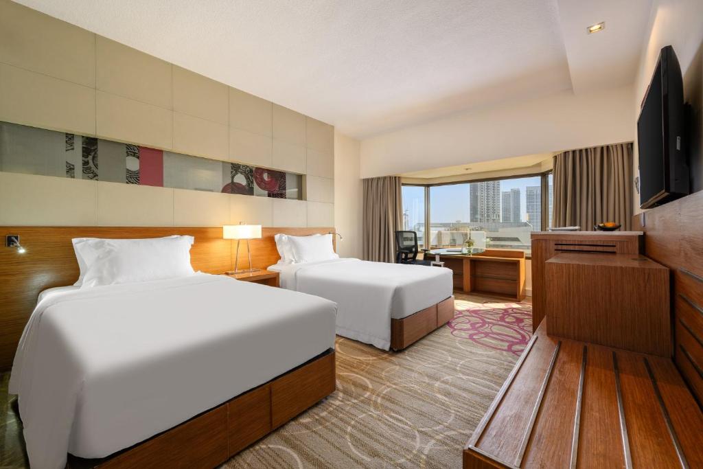 a hotel room with two beds and a television at Centara Grand at Central Plaza Ladprao Bangkok in Bangkok
