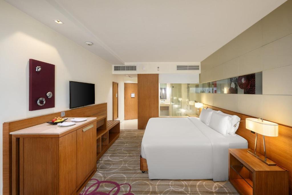a hotel room with a large bed and a television at Centara Grand at Central Plaza Ladprao Bangkok in Bangkok