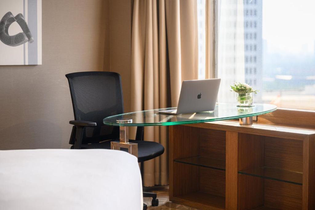 a glass table with a laptop on a desk with a chair at Centara Grand at Central Plaza Ladprao Bangkok in Bangkok