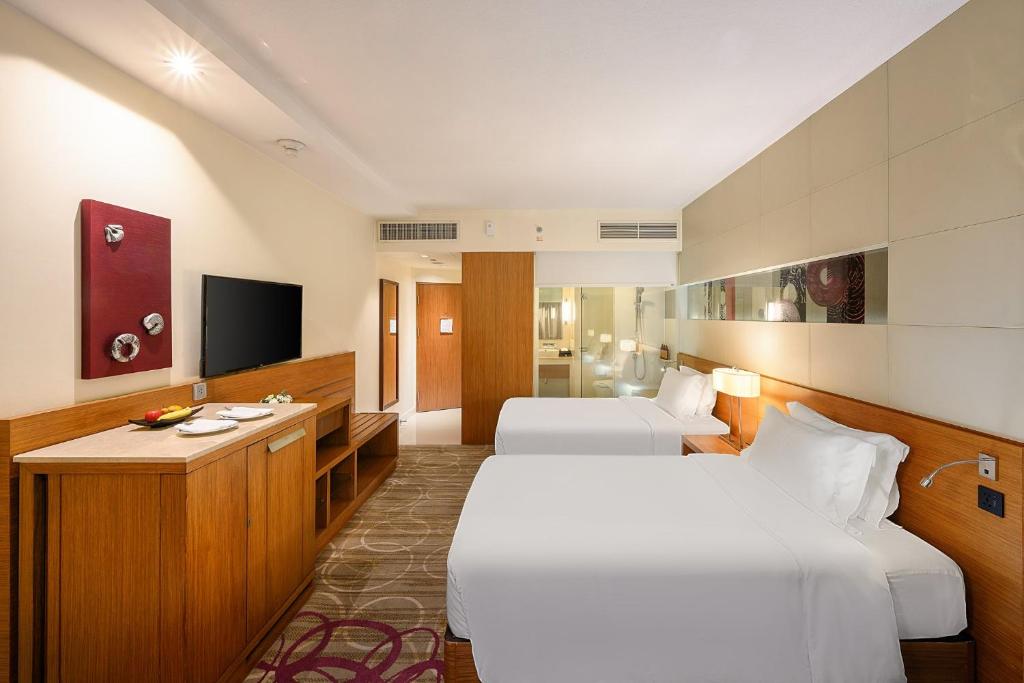 a hotel room with two beds and a television at Centara Grand at Central Plaza Ladprao Bangkok in Bangkok