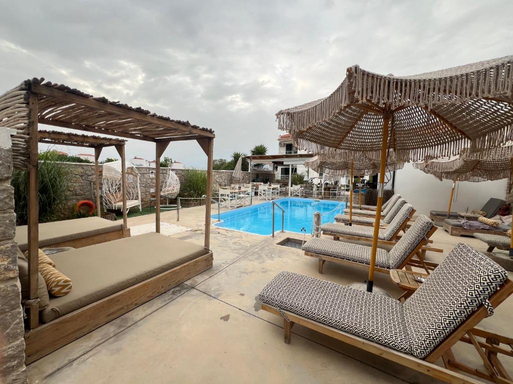 a resort with a swimming pool with chairs and umbrellas at Koukounari Apartments in Skala