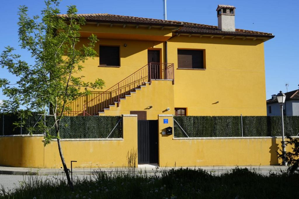 una casa amarilla con una escalera delante de ella en El Mirador de Segovia, en Basardilla