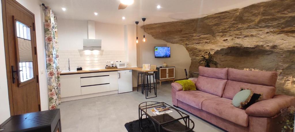 a living room with a couch and a kitchen at Casa Cueva Las Chicas del Puente in Setenil