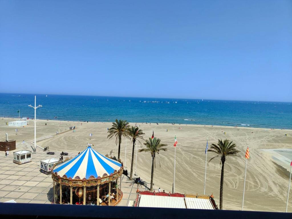een strand met een tent en palmbomen en de oceaan bij Studio cosy vue mer Canet Plage 3étoiles in Canet-en-Roussillon