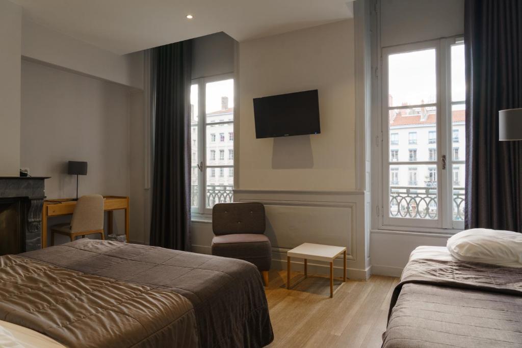 a hotel room with two beds and a television at Hotel du Théatre in Lyon