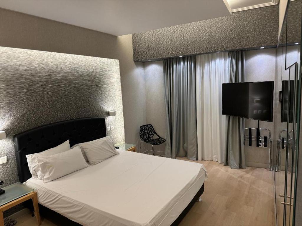 a bedroom with a white bed and a tv at Kreoli Hotel in Athens