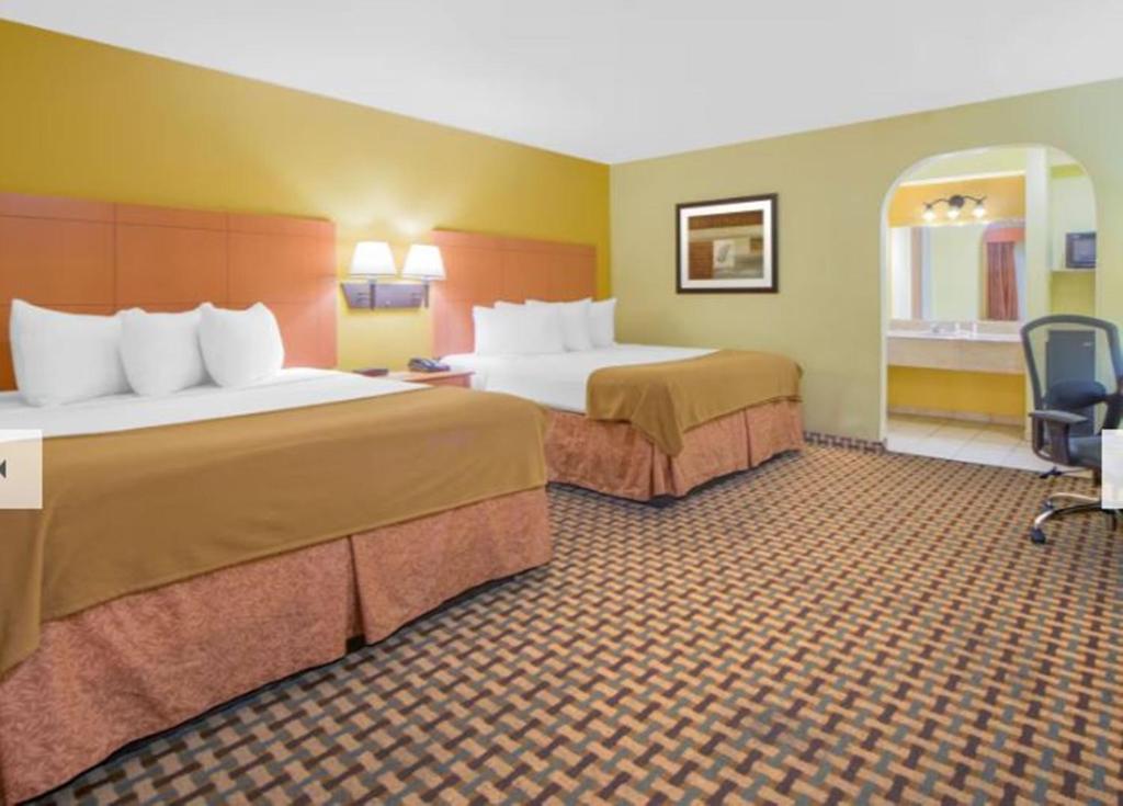 a hotel room with two beds and a chair at Days Inn by Wyndham Lubbock South in Lubbock