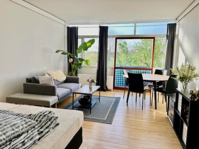 een woonkamer met een bed en een tafel en stoelen bij Skøn arkitekt tegnet ferie lejlighed in Charlottenlund