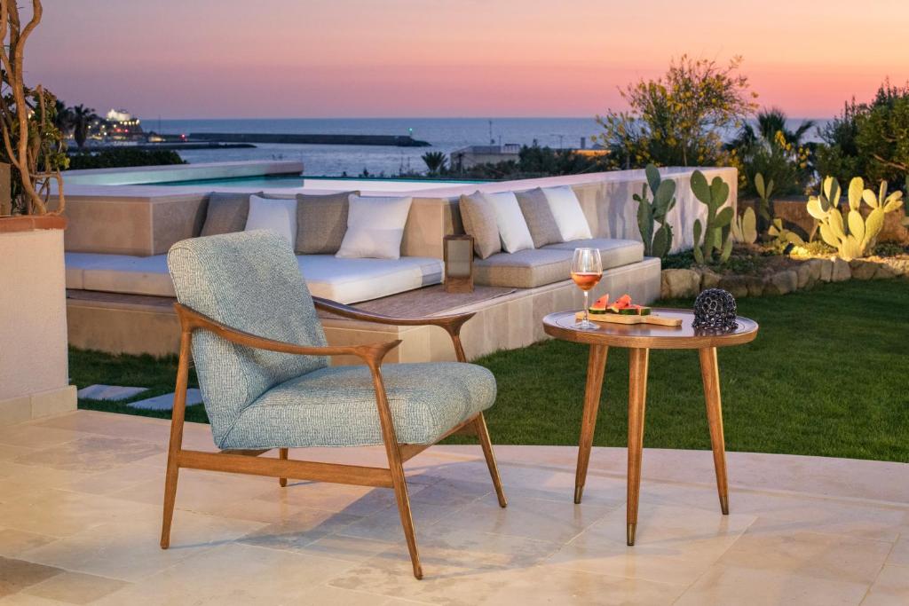 uma cadeira e uma mesa com um copo de vinho no pátio em OraBlu Exclusive Villas em Ischia