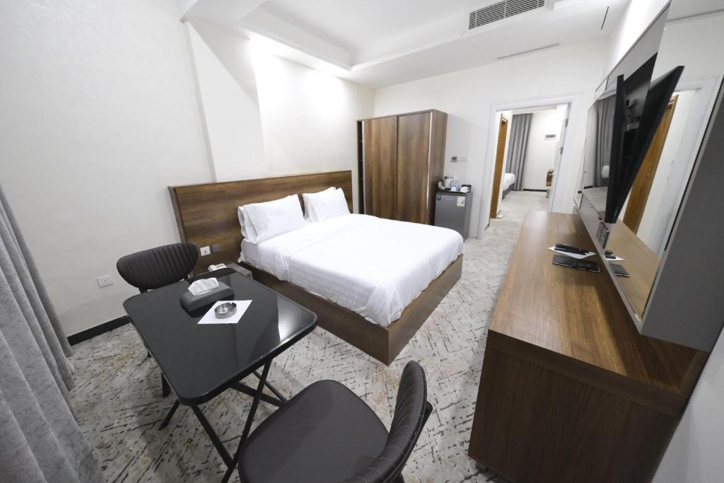 um quarto de hotel com uma cama, uma secretária e uma televisão em Al jadriya Palace em Al Karrādah