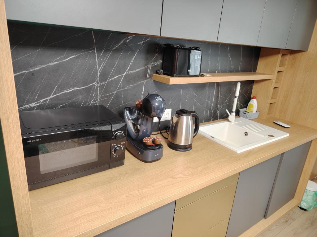 a kitchen counter with a microwave and a sink at Milan Luxury Apartaments I-Maurer Residence Târgu Mureș in Târgu-Mureş