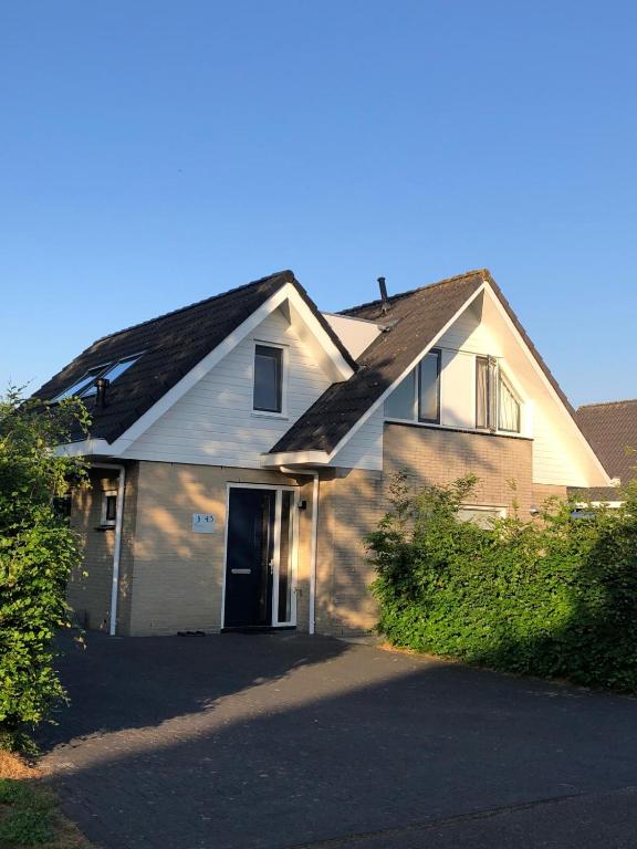 a white house with a black roof and a driveway at Villa Overstag in Terherne